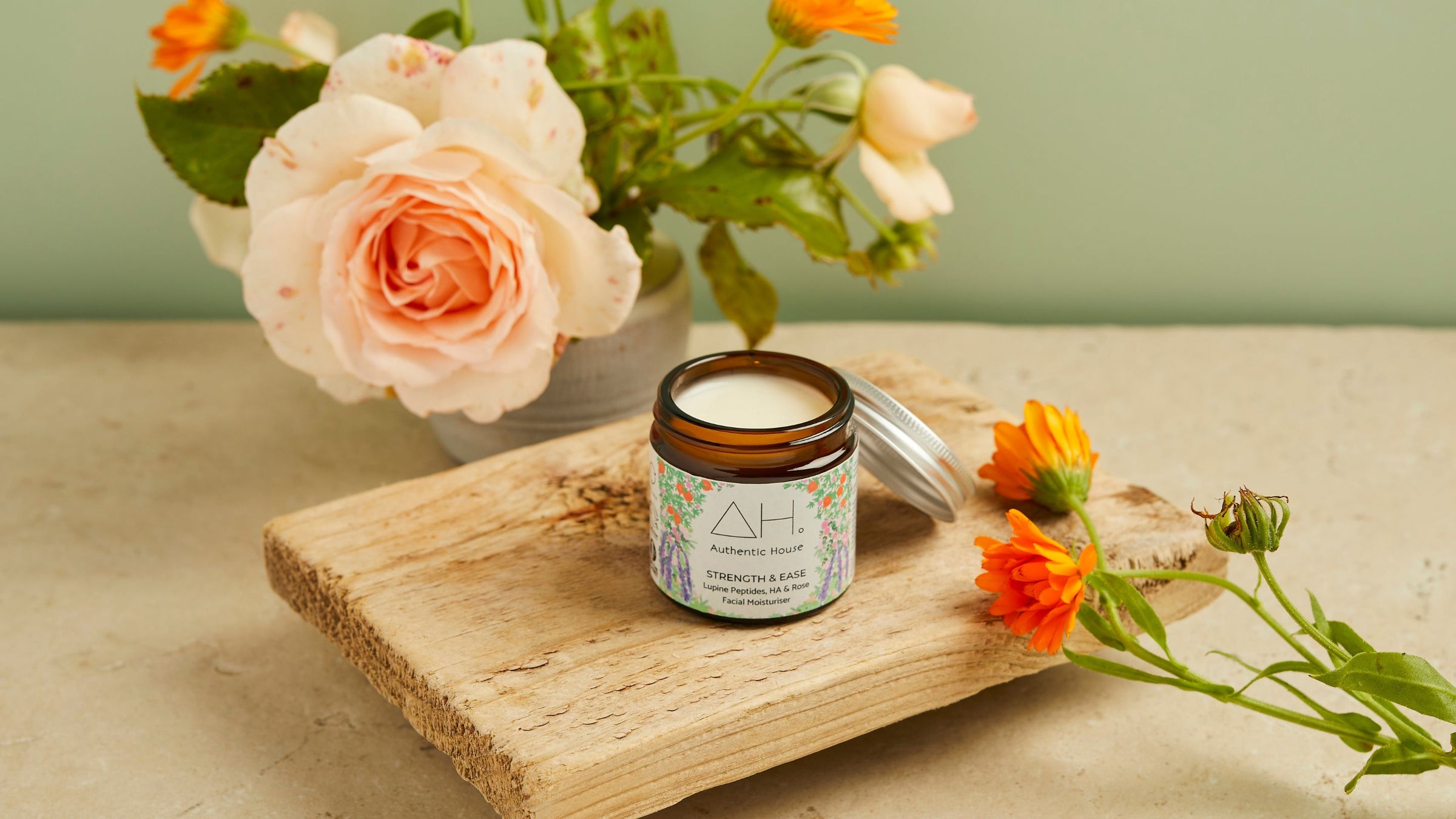 Sustainable self care showing Strength & Ease moisturiser jar with a rose and marigolds
