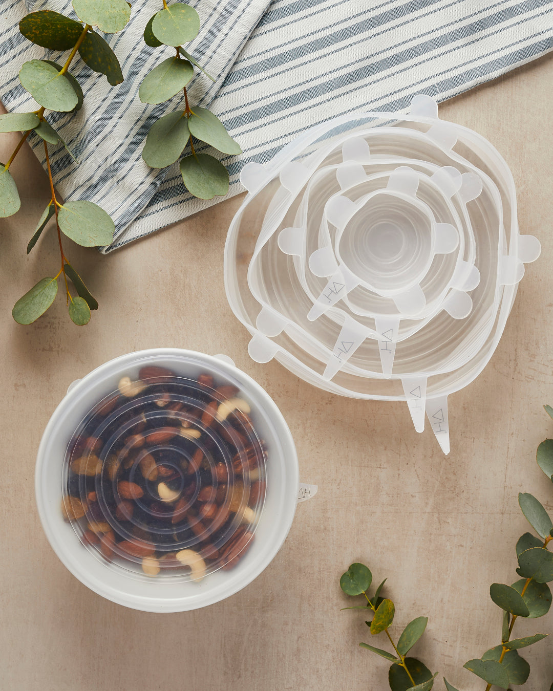 Transparent silicone lids in various sizes, effortlessly stretching over bowls and containers, illustrating their eco-friendly, reusable nature and superior food storage capabilities.